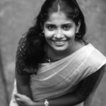 Portrait of a young woman in a traditional sari, smiling warmly.